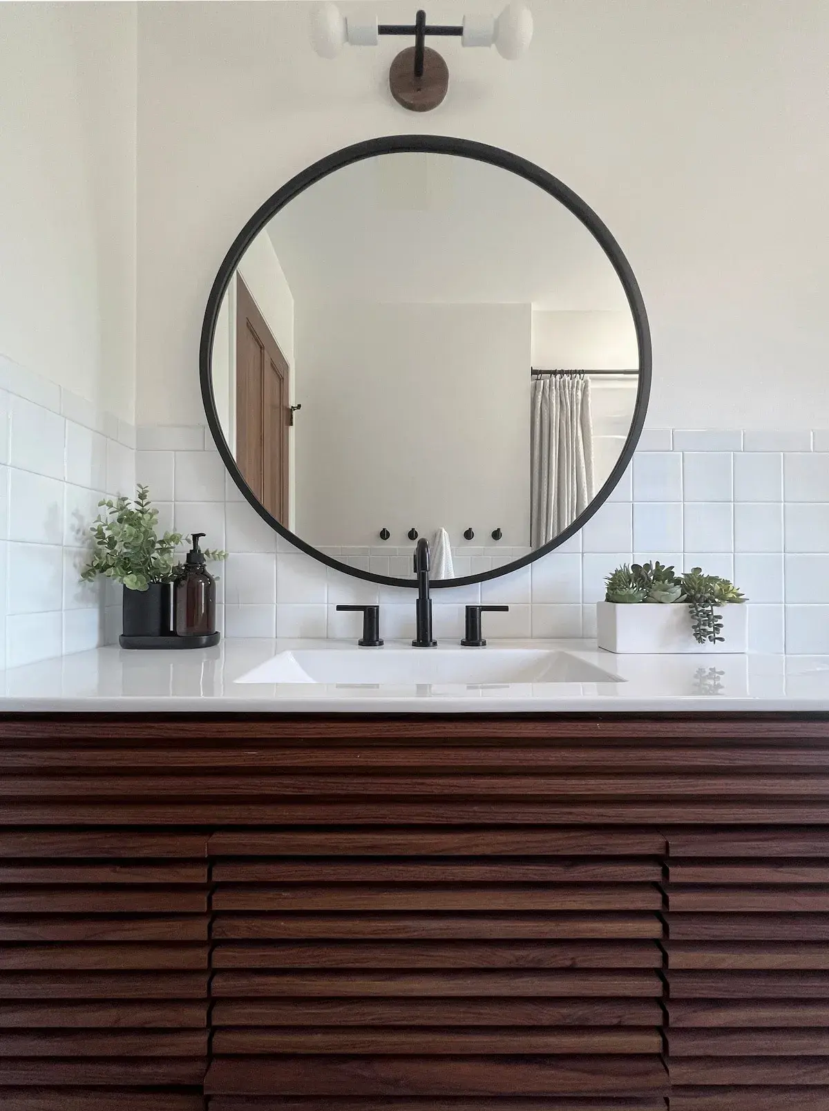Second-floor bathroom, a round mirror over a slatted wood vanity