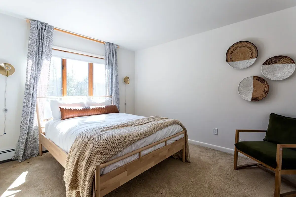 Bedroom 4 at The Acrewoods, a queen bed under a sunny window, woven baskets on the wall