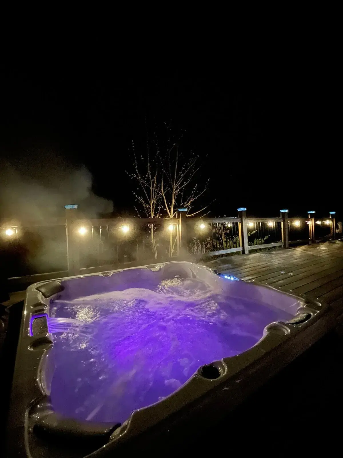 The hot tub on the wrap-around deck at night, steam rising