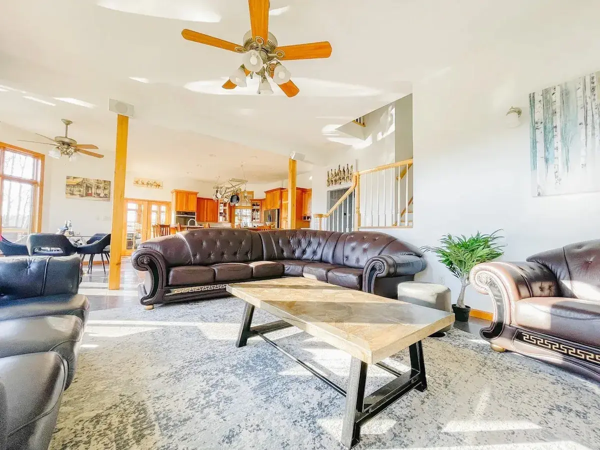 The living room, a leather sectional under a ceiling fan