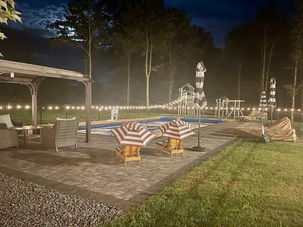 The pool terrace at night under string lights