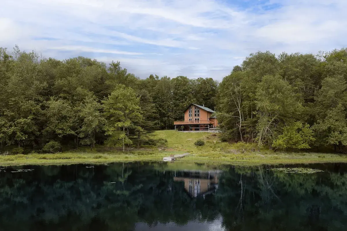 The house across the lake, the treeline reflected in still water
