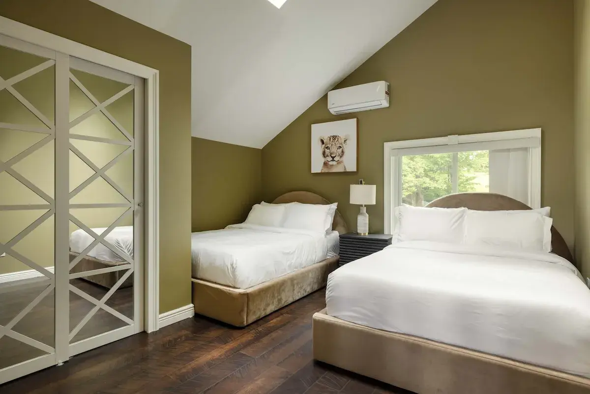 A bedroom with two beds and olive walls