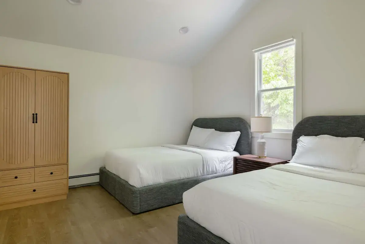 A bedroom with two beds and an armoire